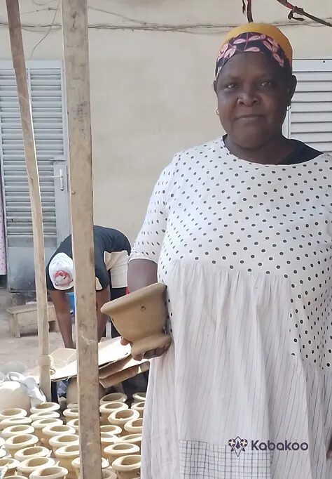 Master potter Noumousso Kané standing in her workshop.
