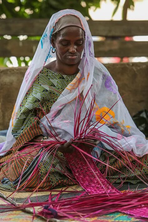 Master weaver Samaou Touré weaving with pink and green fibers.