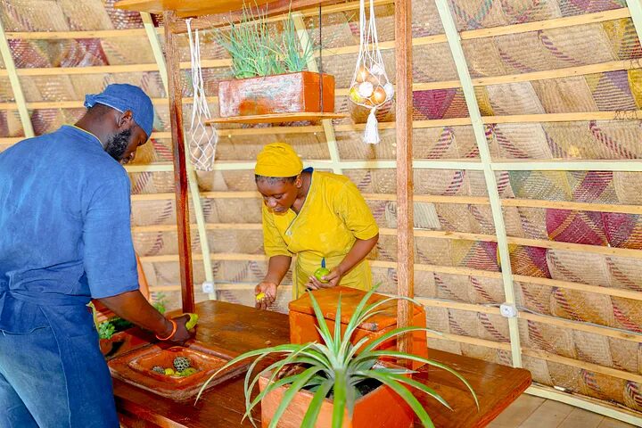 Two makers arrange produce on a TabliCool, a clay-and-wood evaporative cooling table.